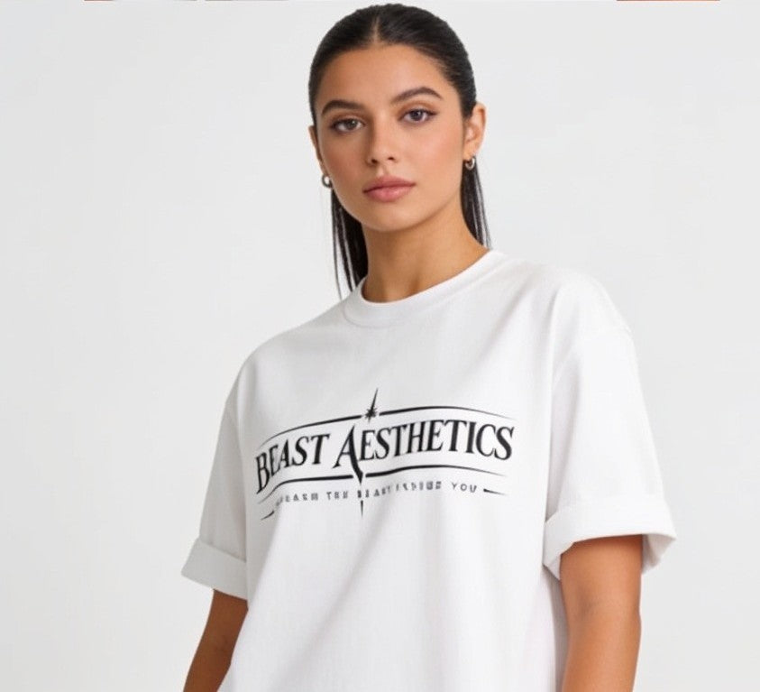 A woman modeling a white oversized t-shirt with a black graphic print that reads 'BEAST AESTHETICS' and 'SEARCH THE BEAUTY INSIDE YOU' on a plain light background.