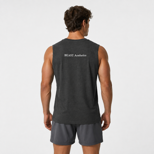 A man viewed from behind wearing a dark charcoal gray sleeveless athletic tank top with 'BEAST Aesthetics' printed in white on the upper back, paired with dark gray shorts, against a light gray studio background.