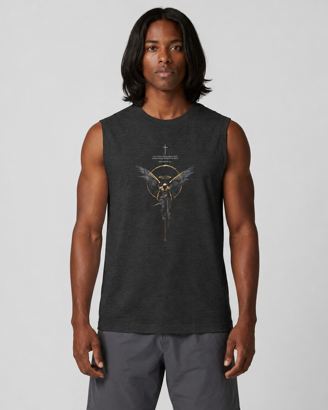A man modeling a dark charcoal gray sleeveless t-shirt with a gold and white graphic of a winged quiver and the text 'The Mockingbird' on the front, paired with gray pants, against a light gray studio background.