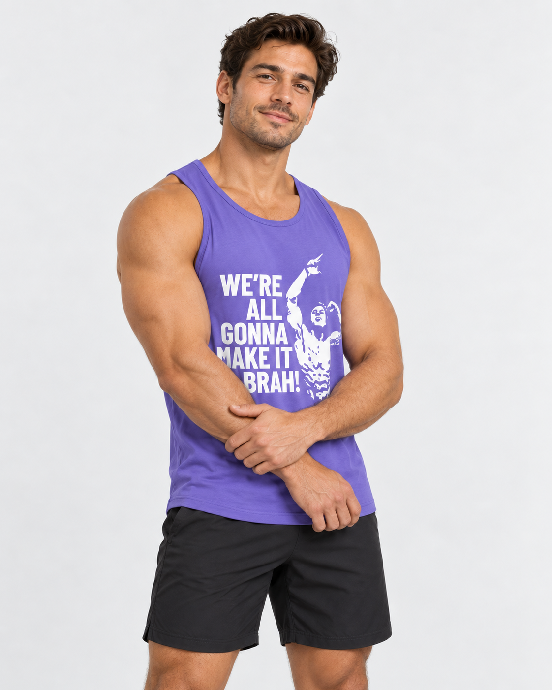 A muscular man wearing a purple athletic tank top with a white graphic and text that reads 'WE'RE ALL GONNA MAKE IT BRAH!' paired with black shorts, standing against a light gray studio background.