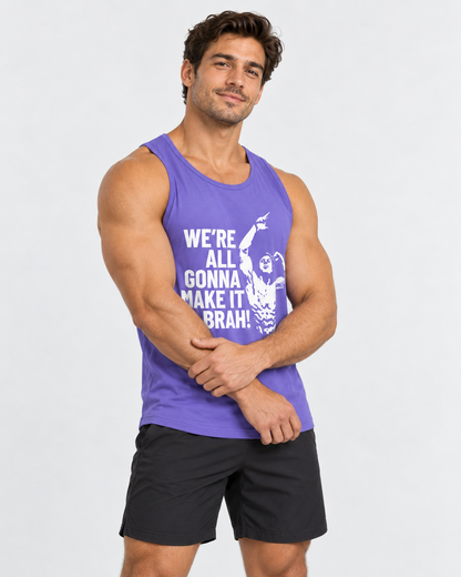 A muscular man wearing a purple athletic tank top with a white graphic and text that reads 'WE'RE ALL GONNA MAKE IT BRAH!' paired with black shorts, standing against a light gray studio background.