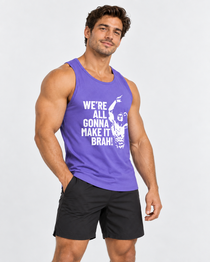 A muscular man wearing a purple tank top with a white graphic print and black athletic shorts, standing against a light gray studio background.