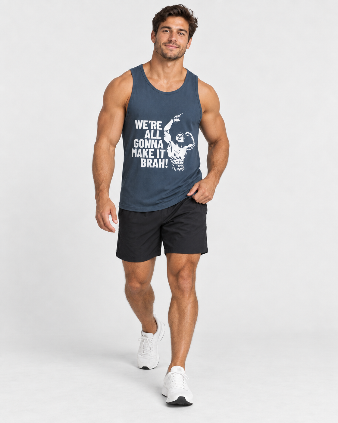 A muscular man wearing a navy blue tank top with a white graphic print and the text 'WE'RE ALL GONNA MAKE IT BRAH', paired with black athletic shorts and white sneakers, walking against a light gray studio background.