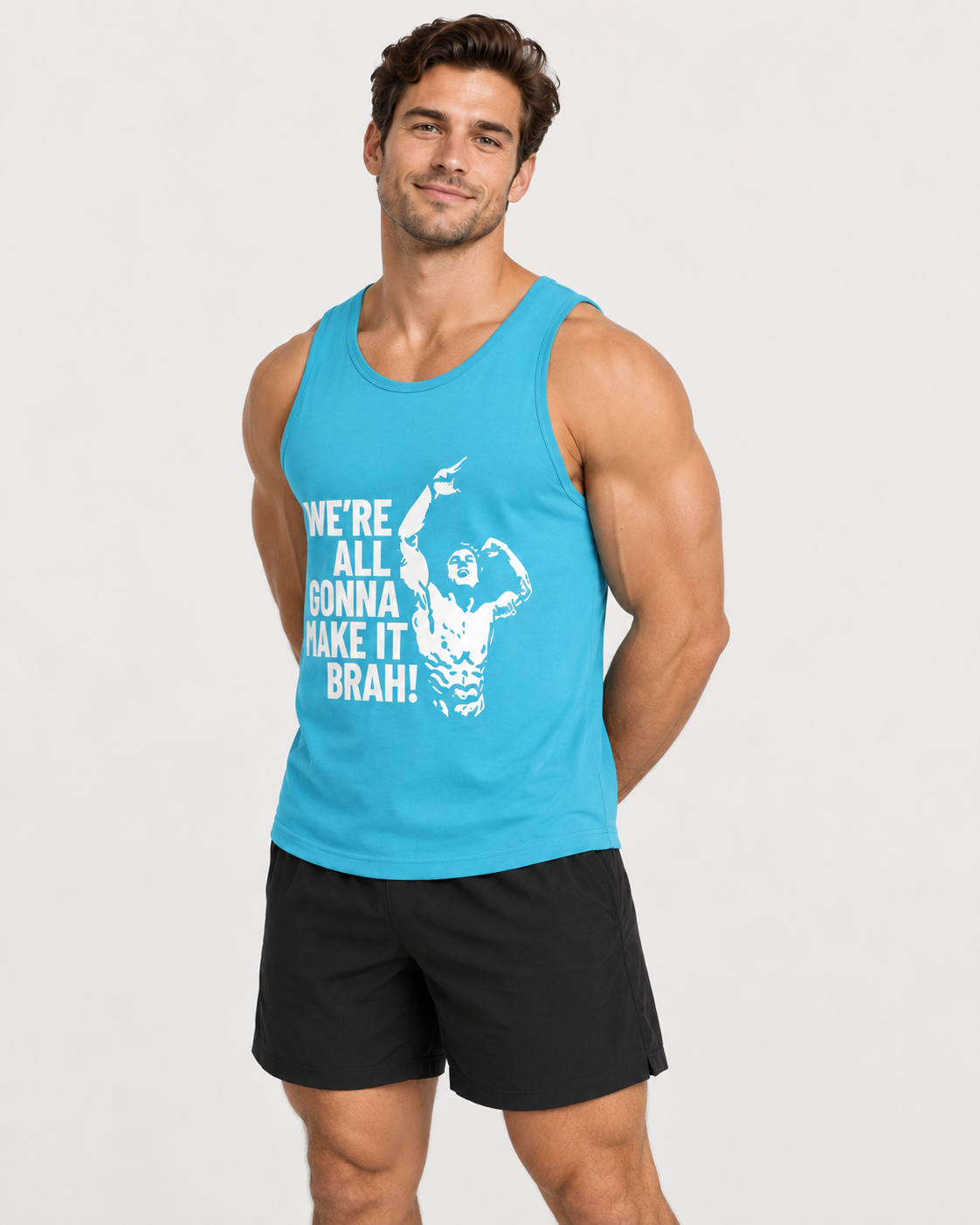 A muscular man wearing a bright blue tank top with a white graphic print that reads 'WE'RE ALL GONNA MAKE IT BRAH!' and black athletic shorts, standing against a light gray studio background.