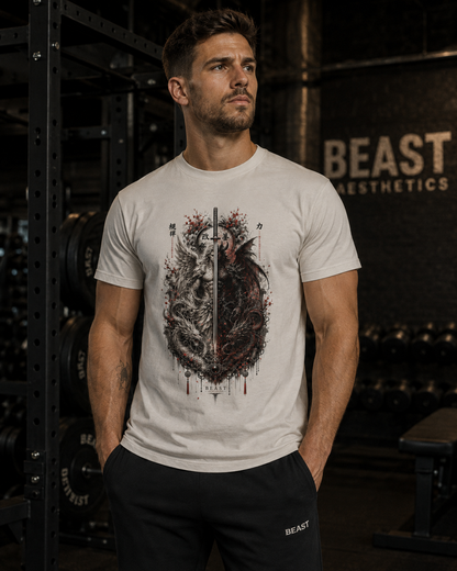 A man in a gym wearing a light gray t-shirt with a detailed graphic of a human heart pierced by a vertical sword, with red splatters and the words 'IN HONOR OF ALL DEATHS'.