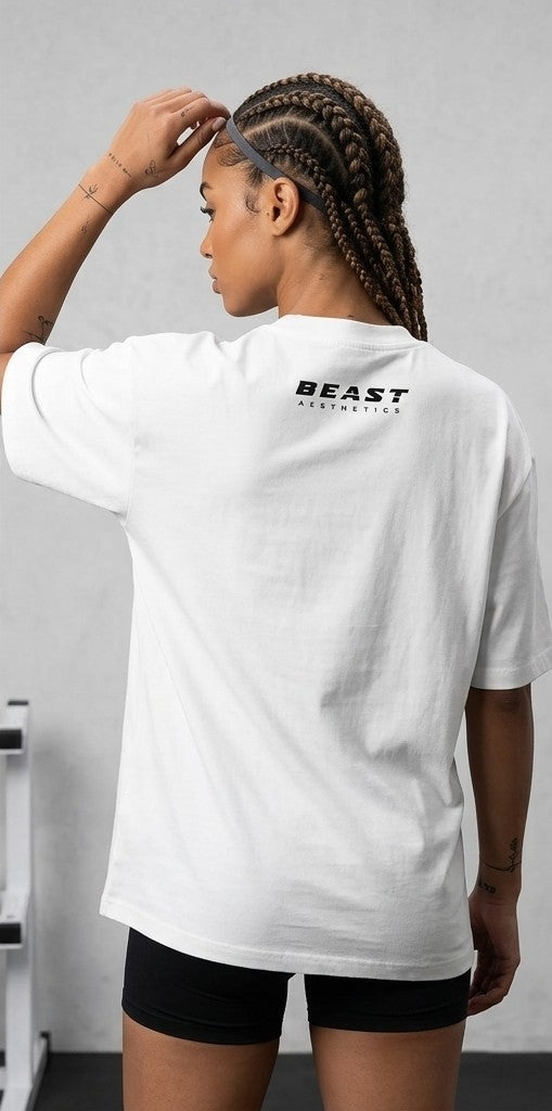 A woman shown from behind wearing a white short-sleeve t-shirt with 'BEAST AESTHETICS' printed in black on the upper back, paired with black shorts.