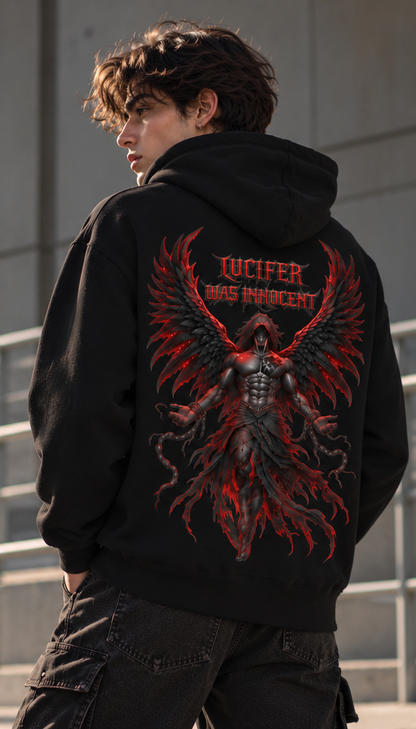 A person shown from the back wearing a black hoodie with a large red and black winged graphic and the text 'JUCIFER WAS INNOCENT' printed on the back, photographed outdoors against a concrete wall.