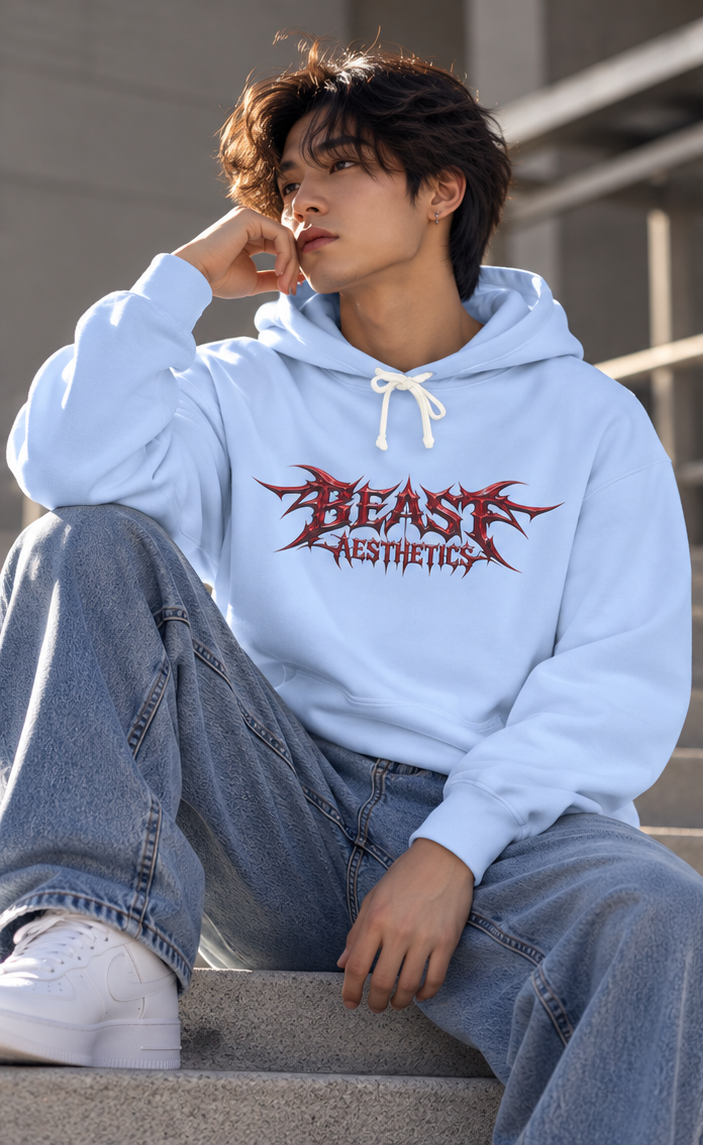 A person sitting on concrete steps wearing a light blue hoodie with a red 'BEAST AESTHETICS' graphic on the chest, paired with loose light-wash jeans and white sneakers.