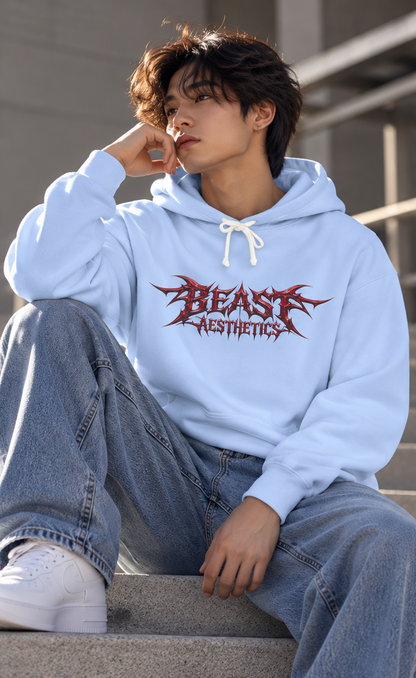A person sitting on concrete steps wearing a light blue hoodie with a red 'BEAST AESTHETICS' graphic on the chest, paired with loose light-wash jeans and white sneakers.