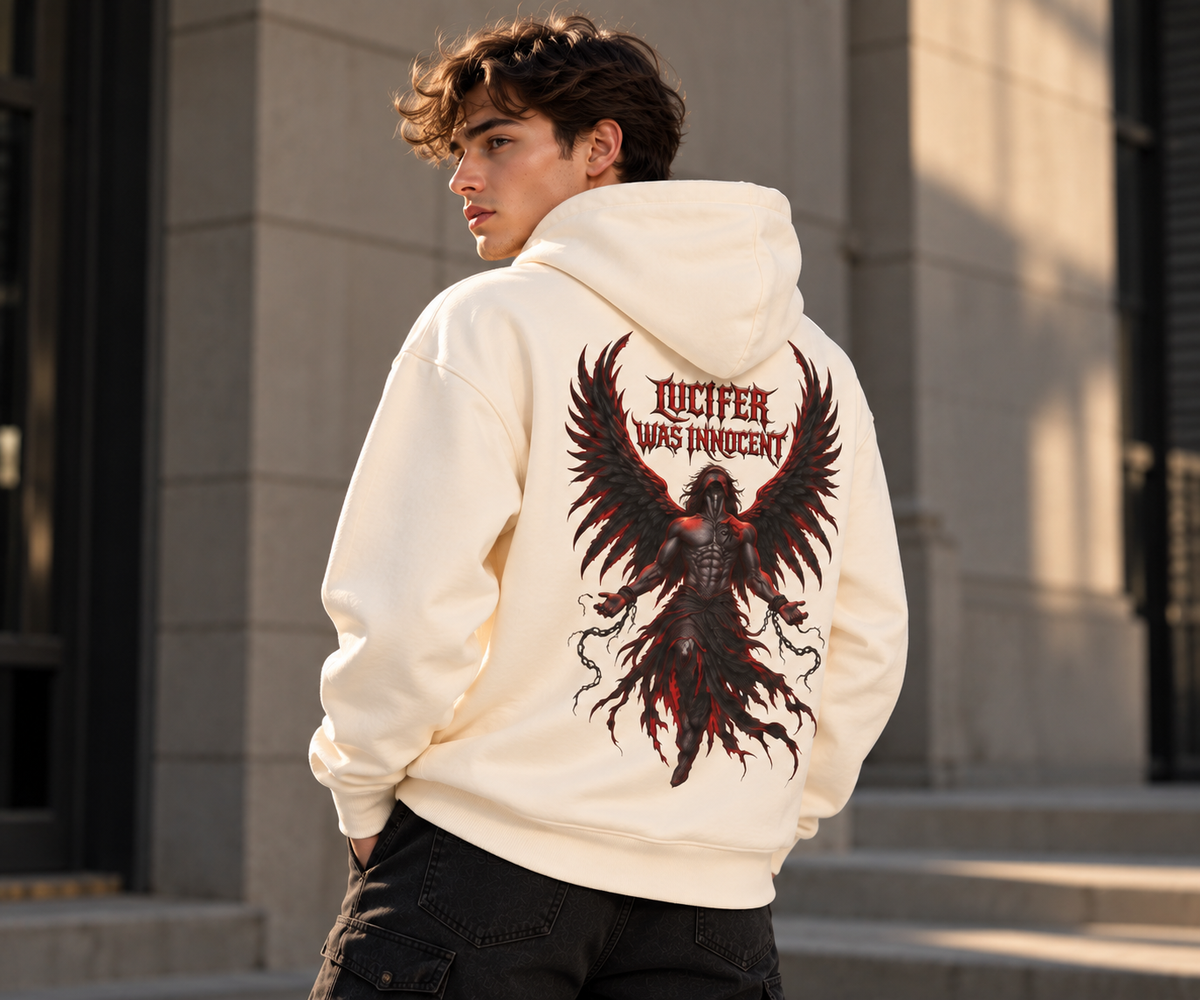 A man wearing a cream-colored hoodie with a large black and red phoenix graphic and the text 'TUTELFER WAS INNOCENT' printed on the back, standing outdoors in front of a stone building.