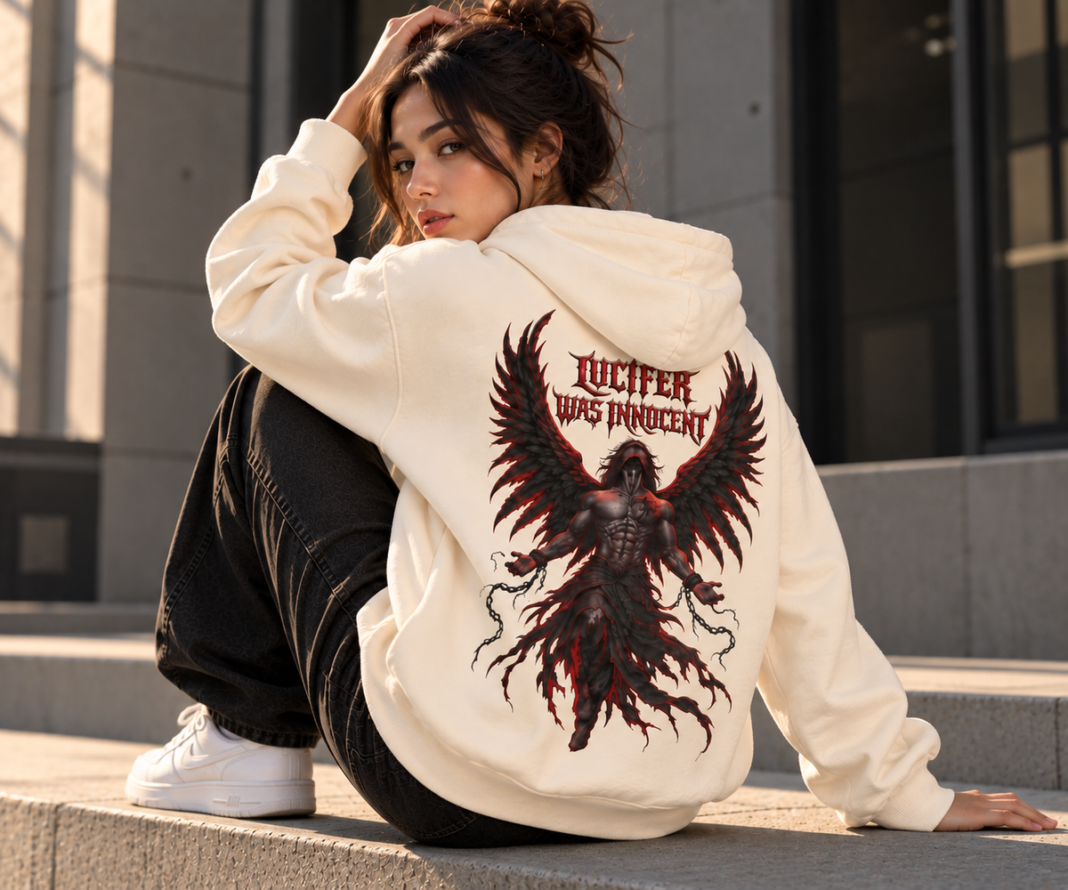 A woman sits on concrete steps outdoors wearing an off-white hoodie with a large back graphic of a dark red and black winged creature and the text 'LUCIFER WAS PRINCESS.' She is also wearing black pants and white sneakers.